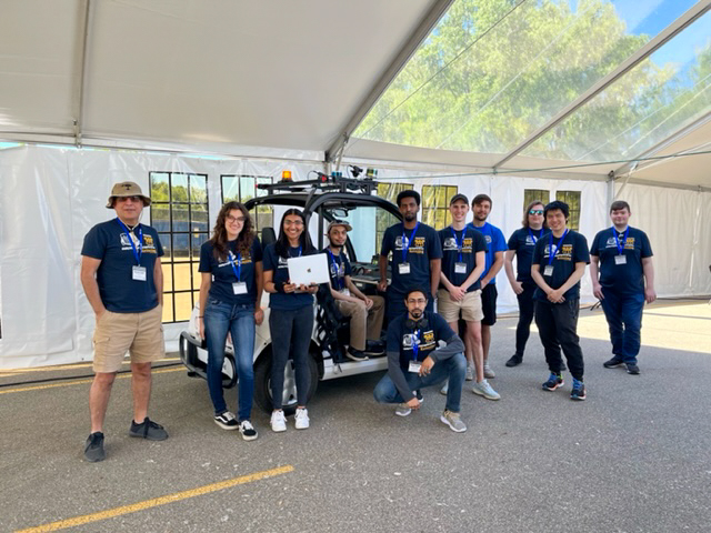 Members of the Kettering University Intelligent Ground Vehicle Competition Team pose in front of their cart.
