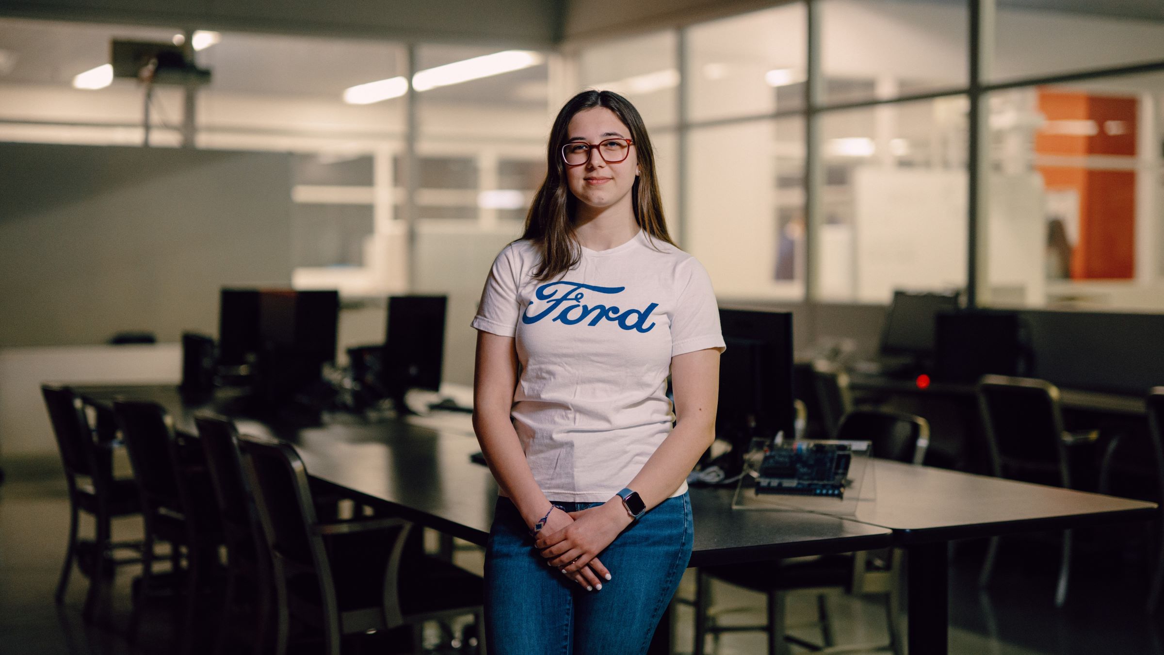 Kettering student Jacqueline Kocik wears a shirt with the Ford logo. She stands in a classroom.