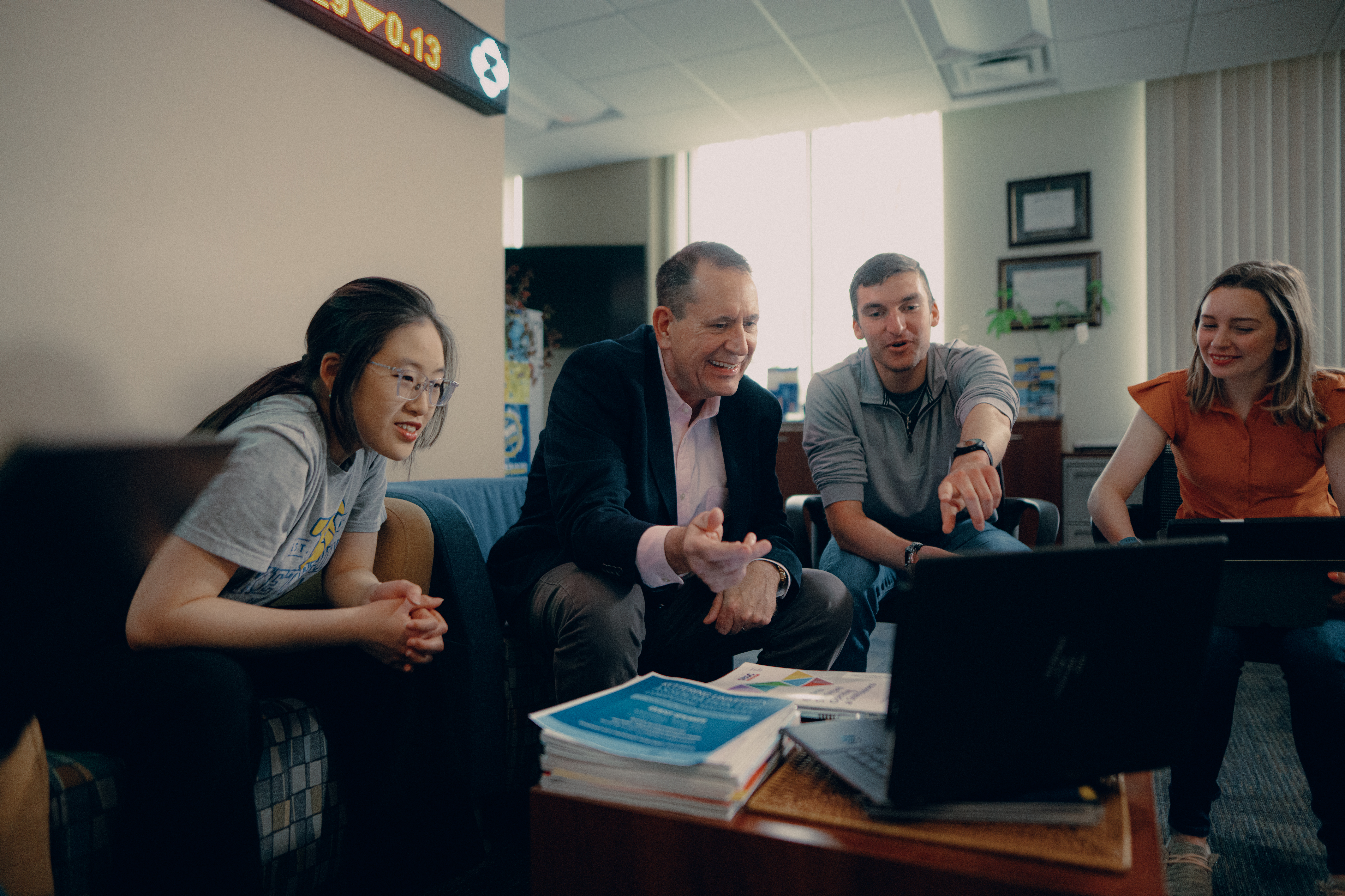 Students and professor looking at laptop