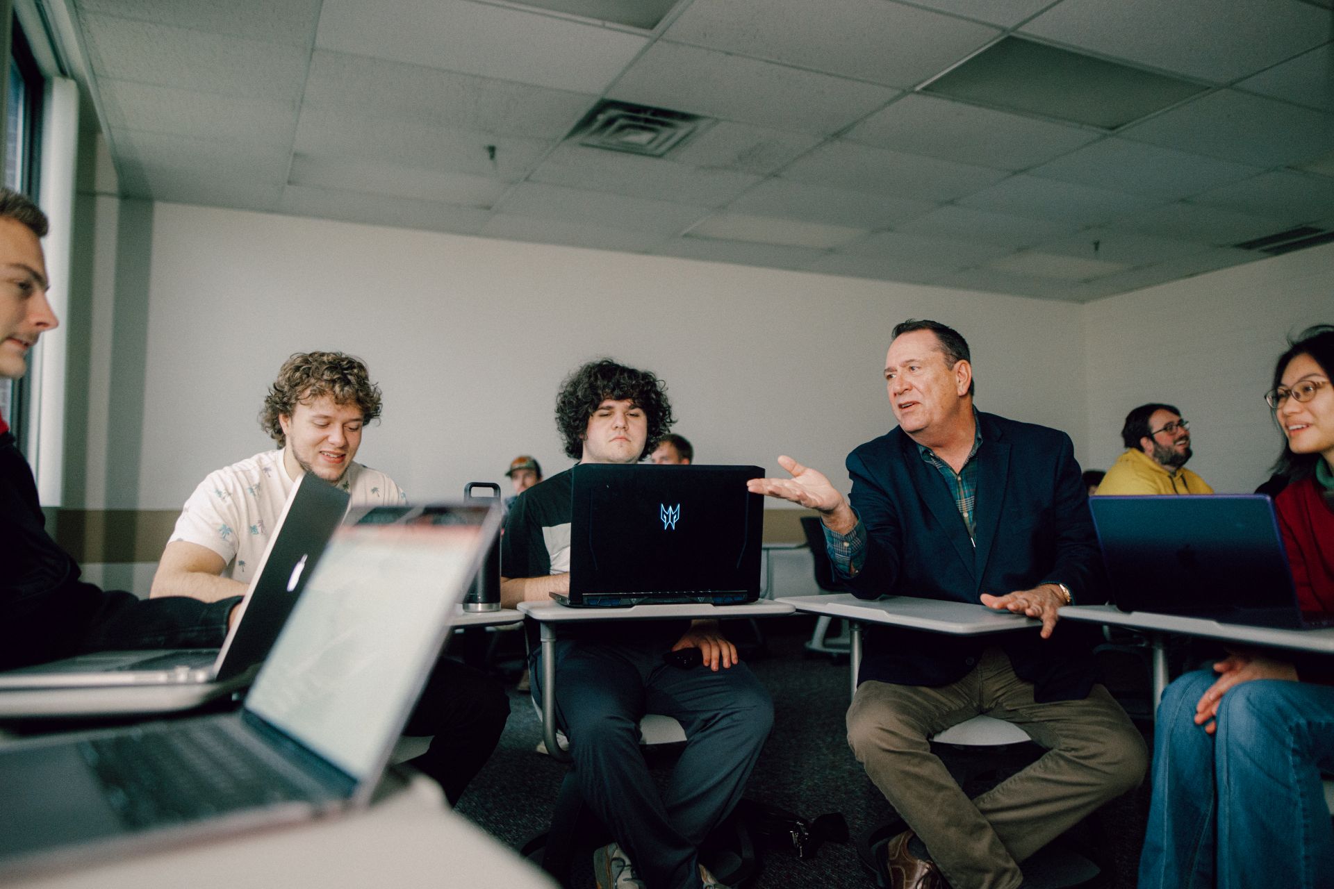 Kettering Managment and Leadership Certificate professor in discussion with a group of students seated at desks in a classroom