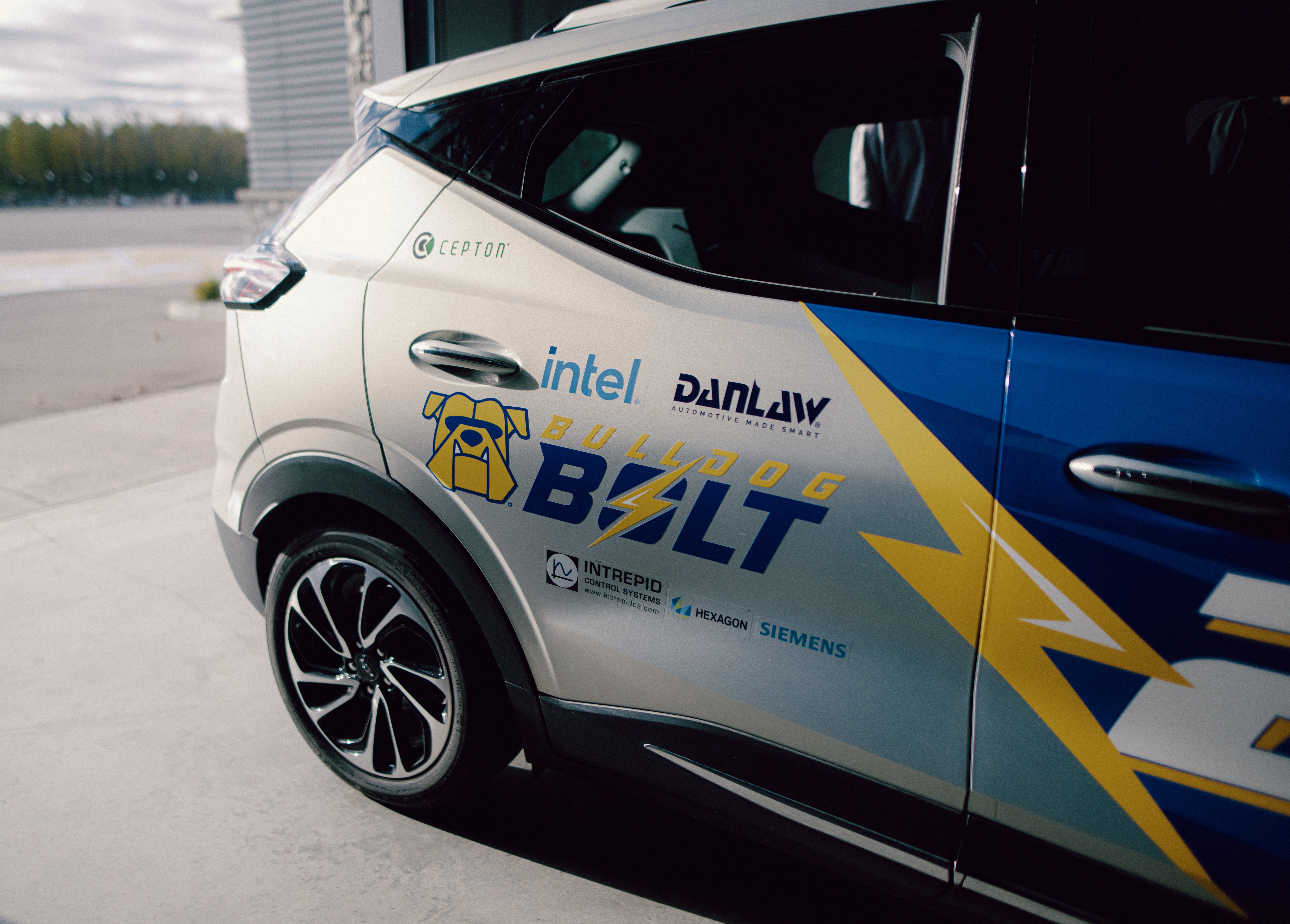 Close-up of the Bulldog Bolt autonomous vehicle featuring a blue, silver and yellow design with the Bulldog Bolt logo and sponsor logos on its side.