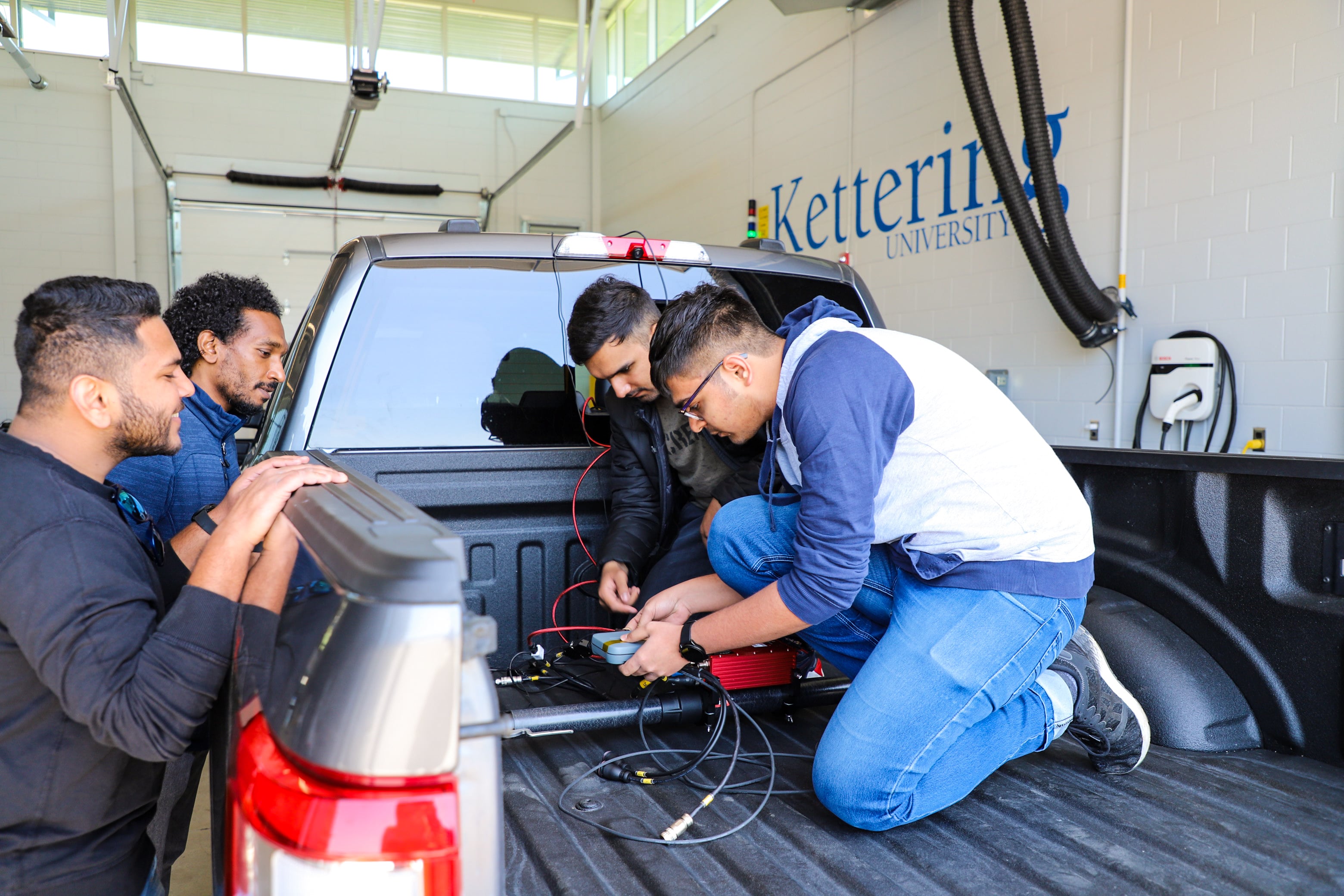 Kettering University graduate students set up testing equipment in the bed of a truck.