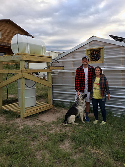 Noah Lukins '19 stands next to Rosie in front of the greenhouse on the reservation