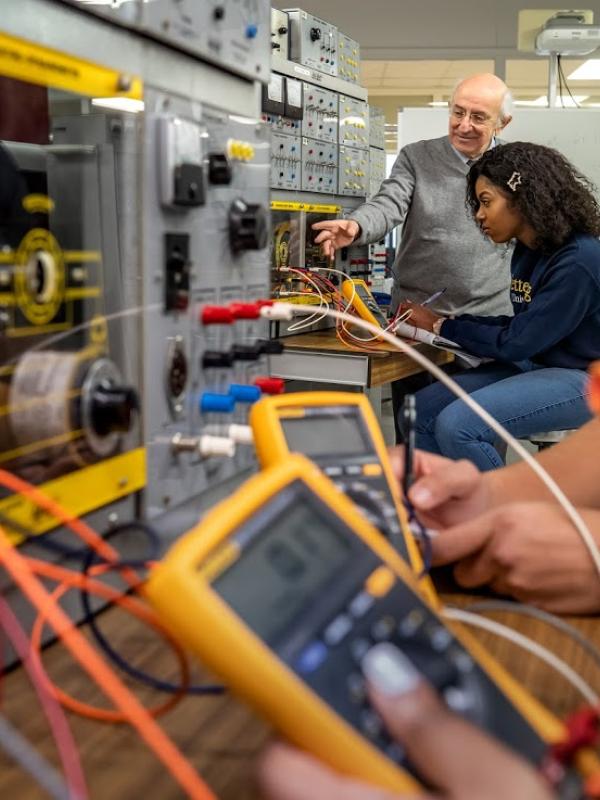 A professor works with a student in a circuits lab.