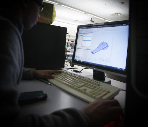 A student creates a component in CAD software while studying machine design.