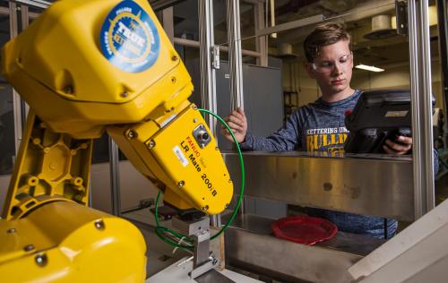An industrial engineering student tests a robotic arm used in manufacturing.