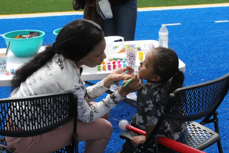 A Kettering University paints the face of a child.
