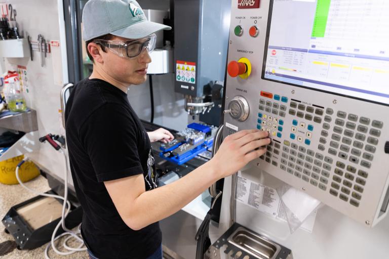 A male Kettering University student changes the settings on a machine.