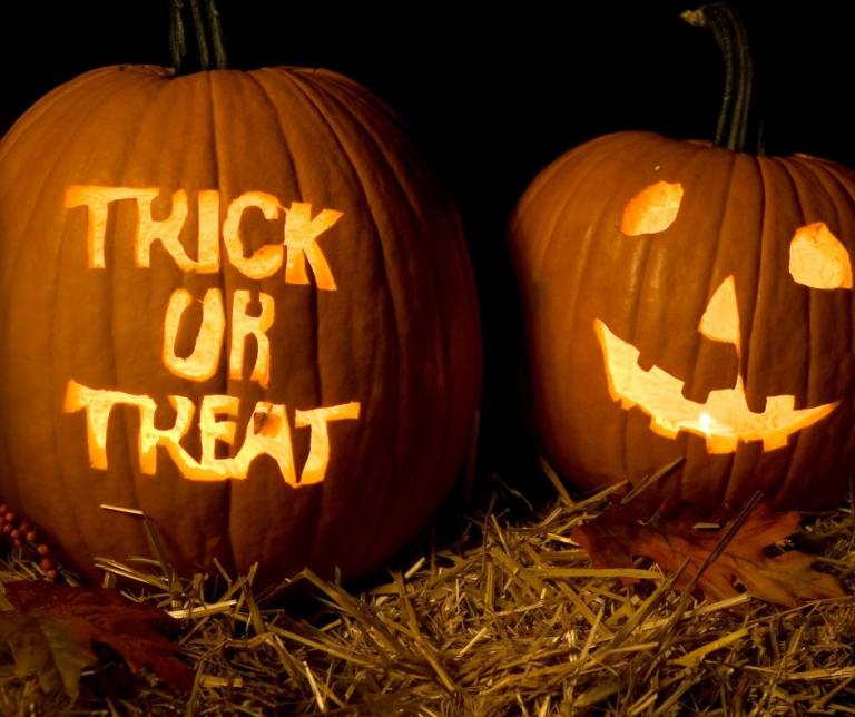 Two pumpkins. One carved to say "Trick or Treat." The other has a face carved into it.