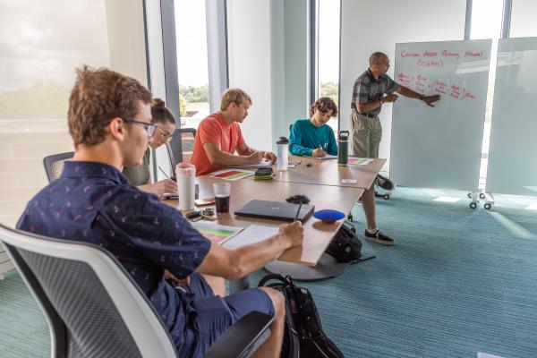 Dr. Ken Williams stands at a whiteboard, explaining the Capital Asset Pricing Model (CAPM) to a room of Kettering University Students