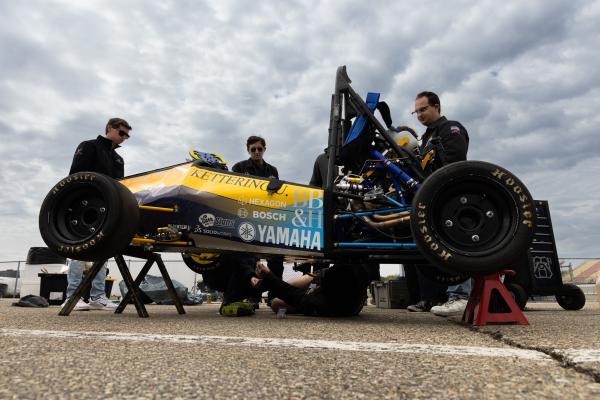 Four members of the Kettering Formula SAE Team Work on their vehicle at Michigan International Speedway