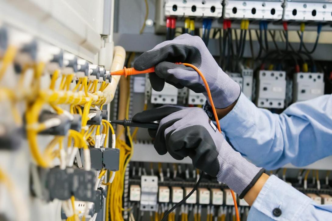 Gloved hands testing voltage in a lab