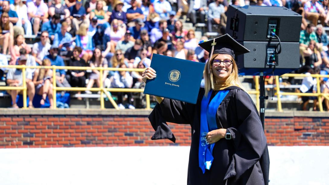 A Kettering University student in cap and gown holding a diploma at graduation