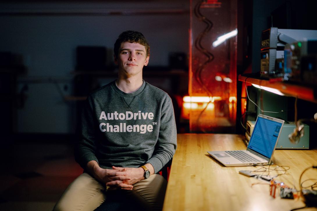 Kettering University engineering management student seated in front of a laptop in a dim, lab setting